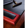 Leather desk pad with a black surface and a pen on a wooden desk